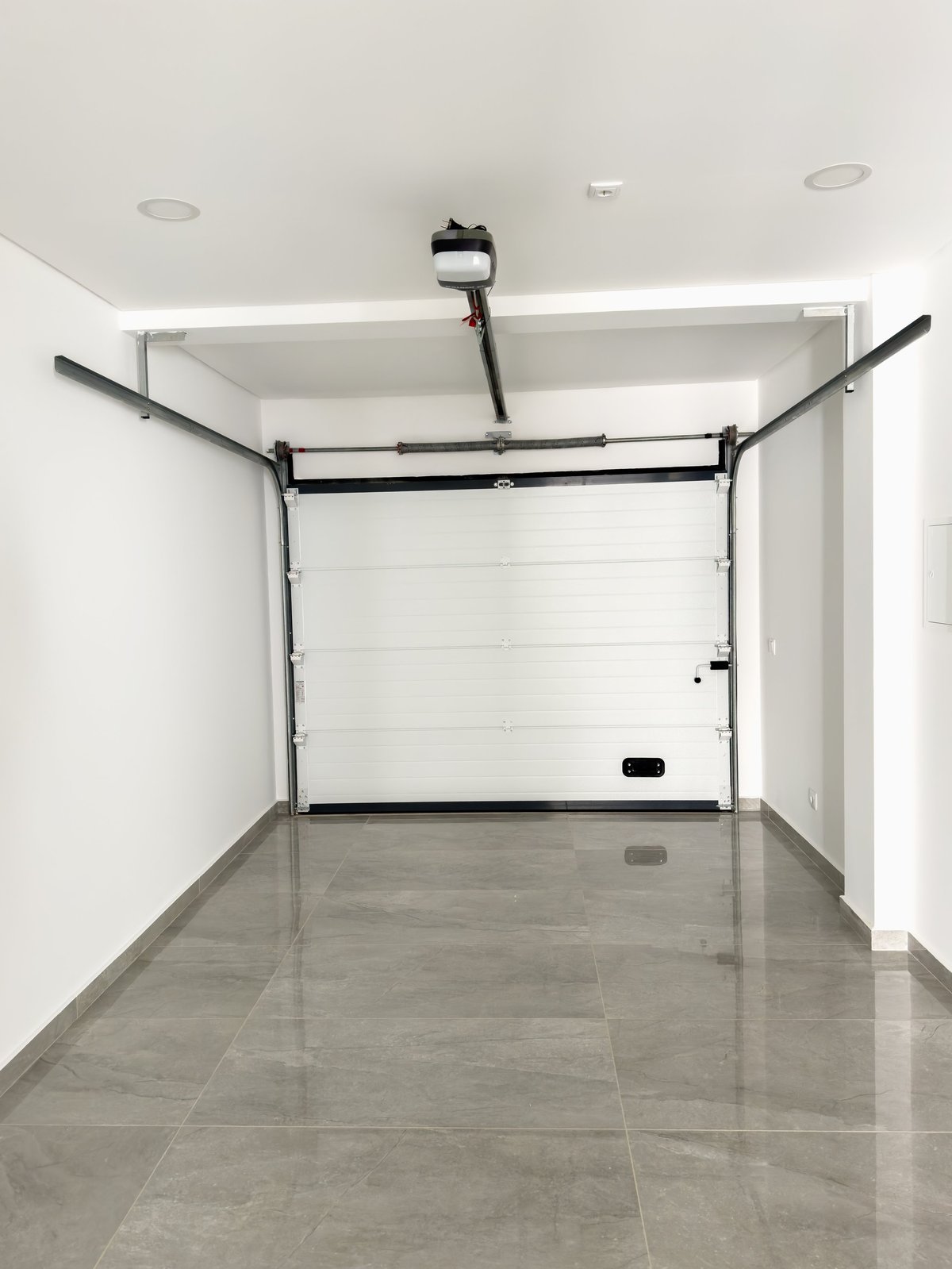 A modern residential garage in Geelong with a white automatic door and polished grey tiled flooring