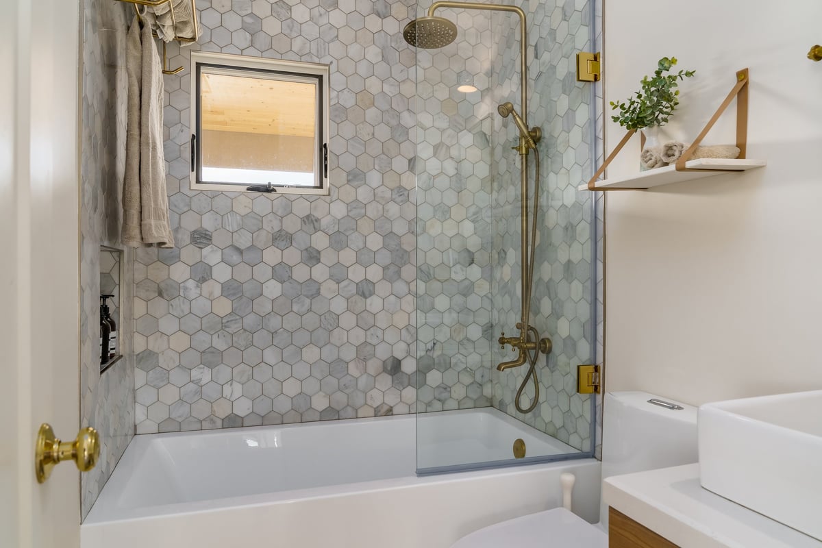 A modern bathroom renovation in Geelong with white tiling and brass fixtures