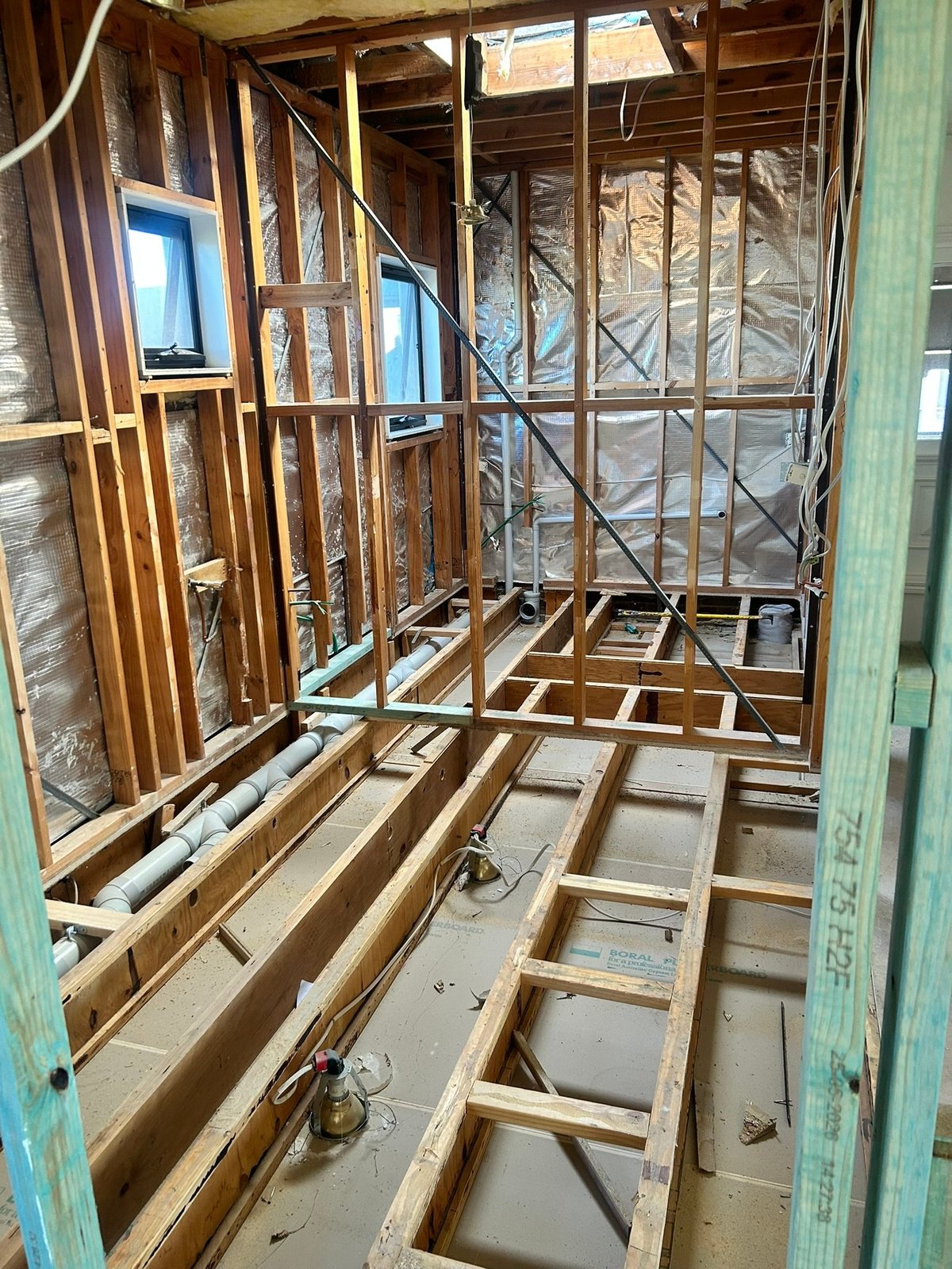 Interior framing of a Geelong home under construction, showing timber studs, floor joists and windows during a Morrissey Built renovation